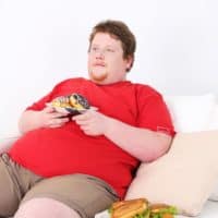 Dicker Mann mit Süßigkeiten auf dem Sofa